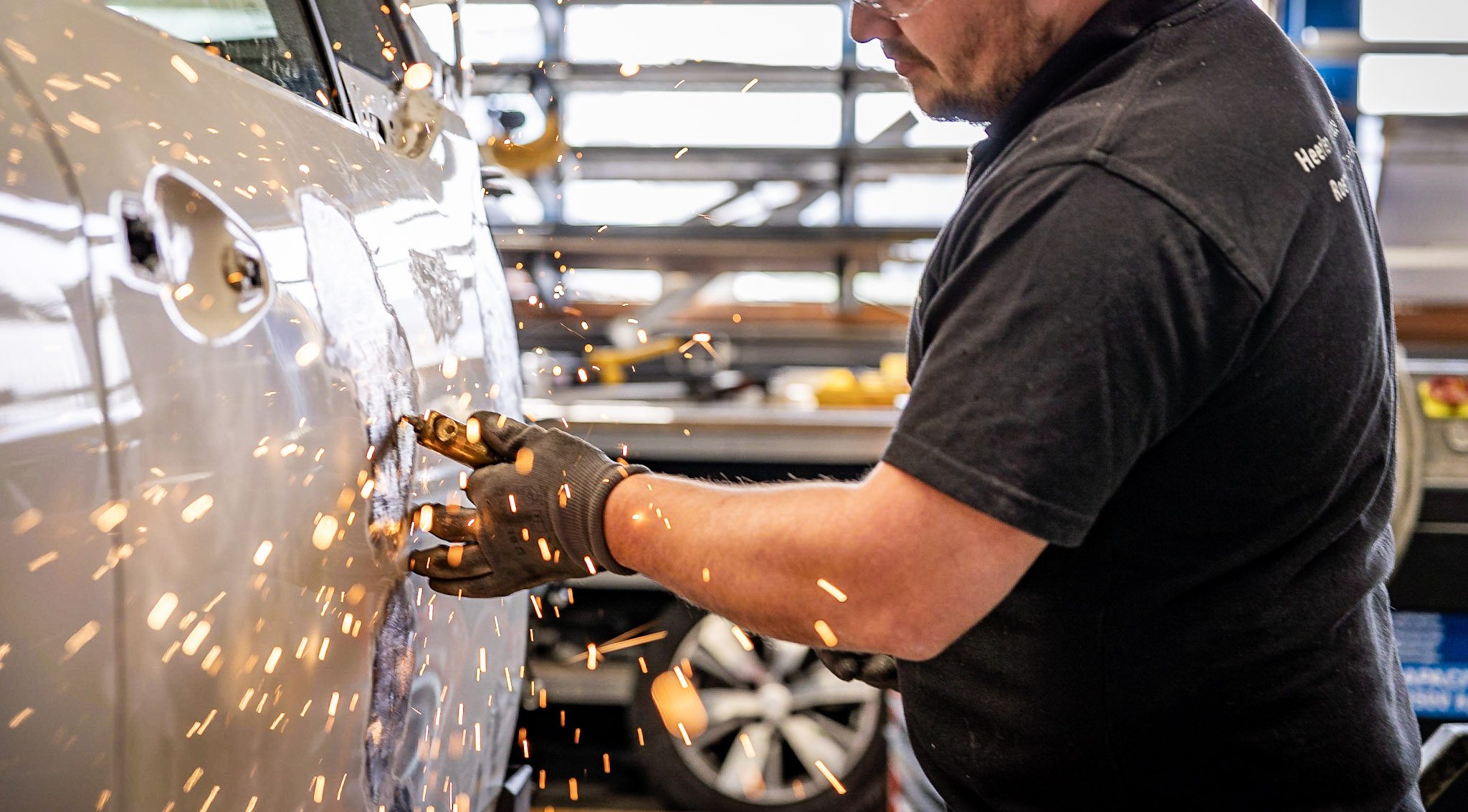 Monteur schuurt plaatwerk van een auto tijdens schadeherstel bij WellColl.